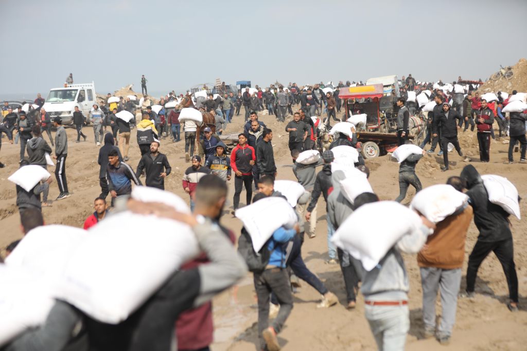 Palestinians receive bags of flour as they wait for aid